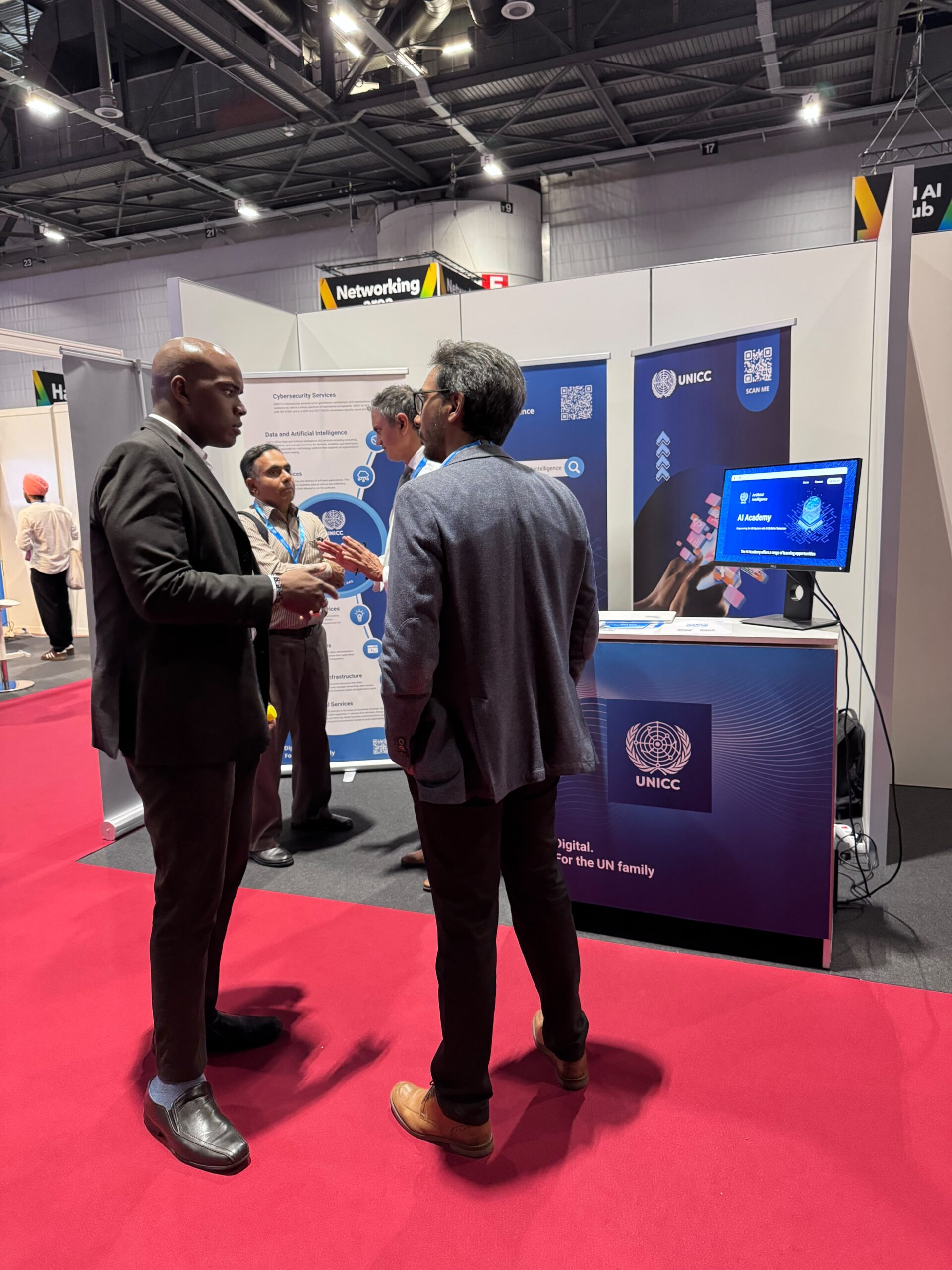 Visitors engage with UNICC representatives at the UNICC exhibition booth during the AI for Good Global Summit 2026, where digital solutions and AI capabilities are showcased through informational displays and live demonstrations.