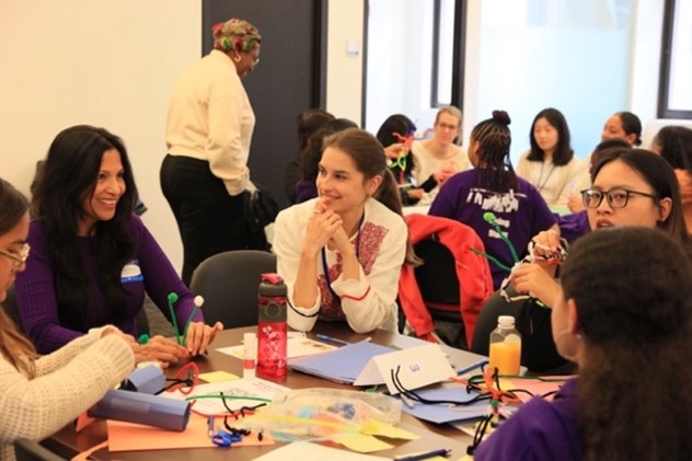 A group of women and middle school children engaging in dialogue in their group.