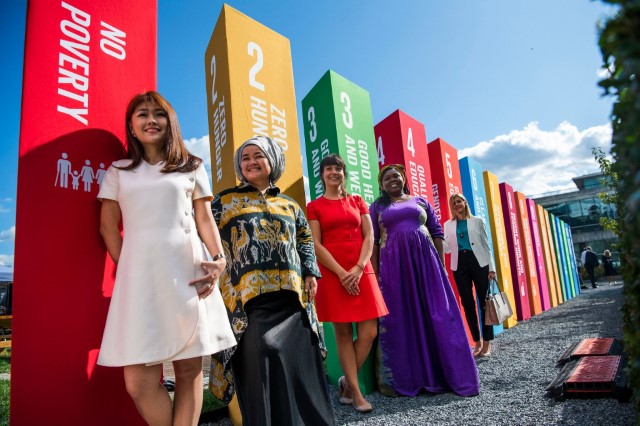 Women standing in front of UN SDG Goal pillars. 